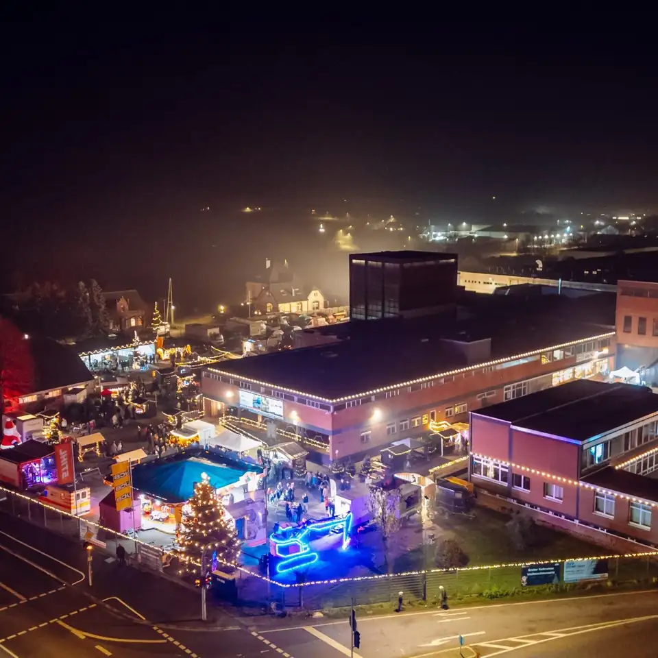 Luftaufnahme des Markts mit Weihnachtsbaum und Eisbahn zwischen den Hallen