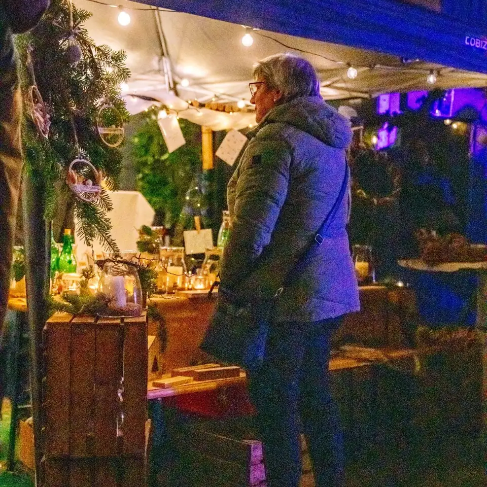 Besucherin an einem Stand mit handgemachter Weihnachtsdekoration