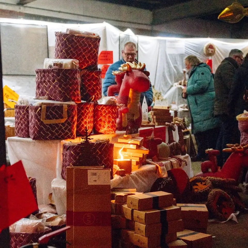 Stand mit Geschenkkörben, davor Besucher im Gespräch