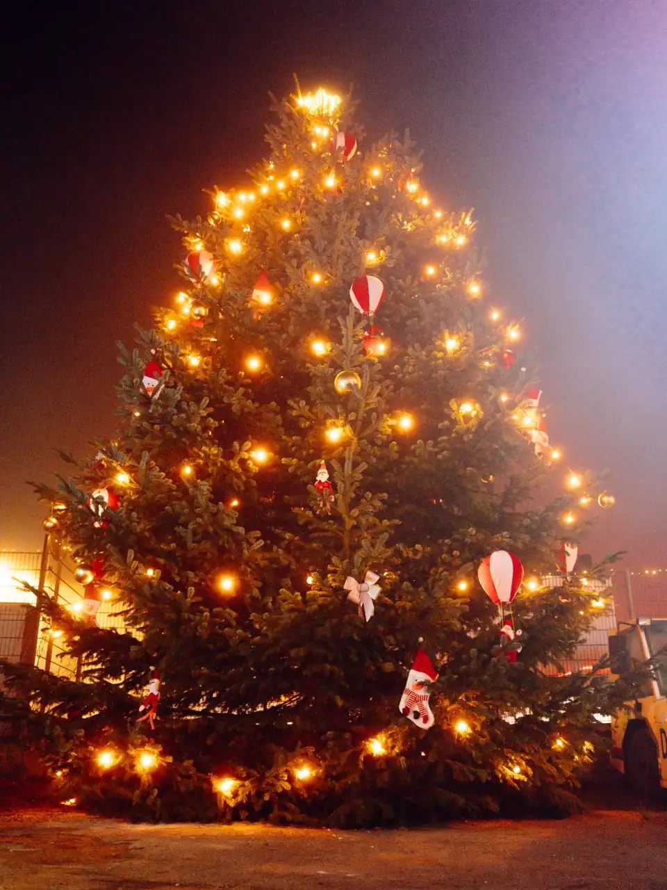 Geschmückter Weihnachtsbaum mit warmen Lichtern im Abendnebel